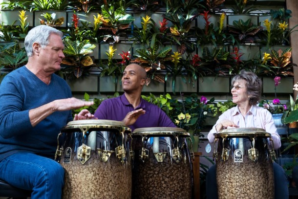 Three individuals sitting in a circle playing drums.