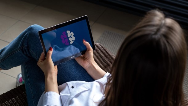 Woman holding a tablet displaying image of a brain