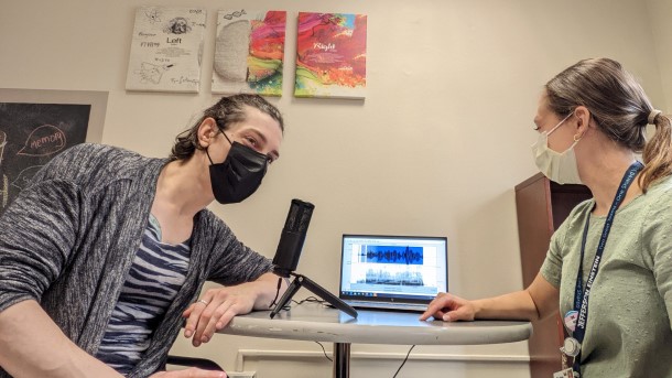 A patient and therapy looking at vocal patterns on a computer.