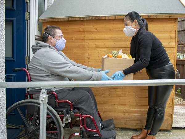 Man in wheelchair receiving grocery delivery.