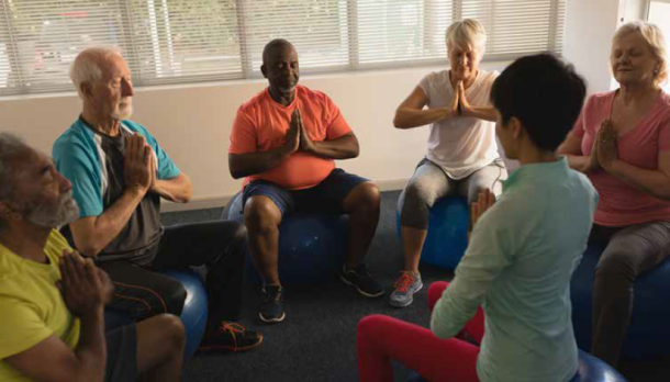 A group of people sitting in a circle with the palms of their hands facing each in front of their hearts.